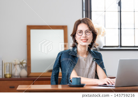 在客廳裡使用電腦的中年女人 在客廳裡使用電腦的中年女人 143759216