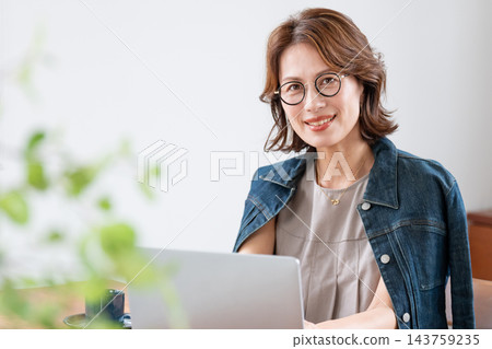 在客廳裡使用電腦的中年婦女 在客廳裡使用電腦的中年婦女 143759235