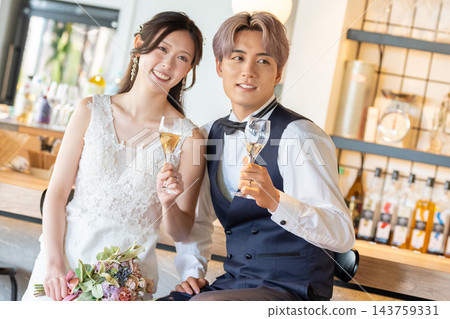 A smiling wedding couple toasting at the bar counter. A smiling wedding couple toasting at the bar counter. 143759331