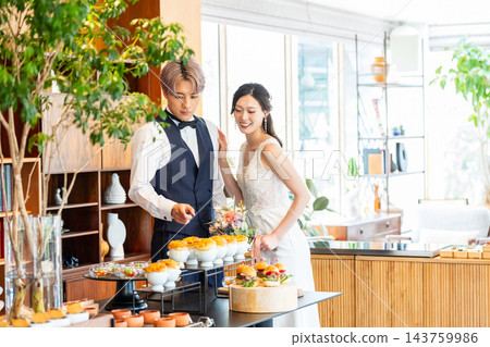 The bride and groom smile in front of the food at their wedding party. The bride and groom smile in front of the food at their wedding party. 143759986