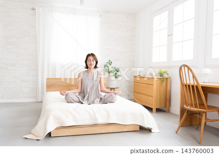 中年婦女在床上伸展身體 中年婦女在床上伸展身體 143760003