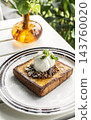 gourmet sweet french toast with madagascar vanilla ice cream and organic honey roasted granola on white cafe table outdoor 143760020