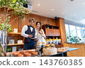 The bride and groom smile in front of the food at their wedding party. 143760385