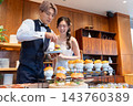 The bride and groom smile in front of the food at their wedding party. 143760389