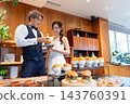 The bride and groom smile in front of the food at their wedding party. 143760391