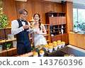 The bride and groom smile in front of the food at their wedding party. 143760396