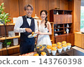 The bride and groom smile in front of the food at their wedding party. 143760398
