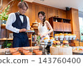 The bride and groom smile in front of the food at their wedding party. 143760400