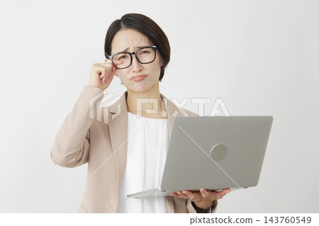 一位中年女商人對著筆記型電腦哭泣，背景是白色。 143760549