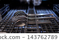 Metallic Spoons And Forks Rest Horizontally Inside Dishwasher Tray. Silverware Pieces Wait Systematically Lined Up Across Plastic Shelf Rack To Undergo Sanitizing Home Culinary Cleaning Cycle. 143762789