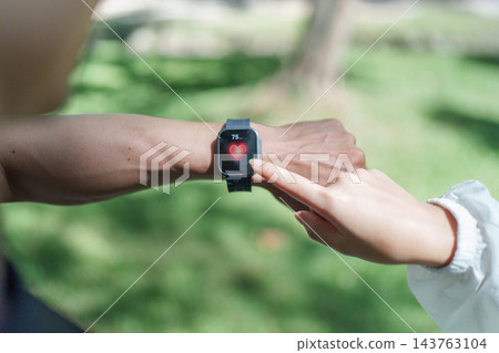 Outdoor exercise partners check a fitness watch Outdoor exercise partners check a fitness watch 143763104