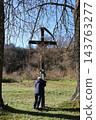 A man stands beneath a wooden cross and embraces it. 143763277