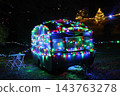 Vintage caravan parked outdoors at night, wrapped in colorful Christmas lights. 143763278