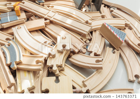 Wooden toy train tracks and railway construction pieces scattered on white background Wooden toy train tracks and railway construction pieces scattered on white background 143763371