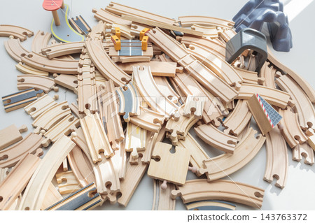 Wooden toy train tracks and railway construction pieces scattered on white background Wooden toy train tracks and railway construction pieces scattered on white background 143763372