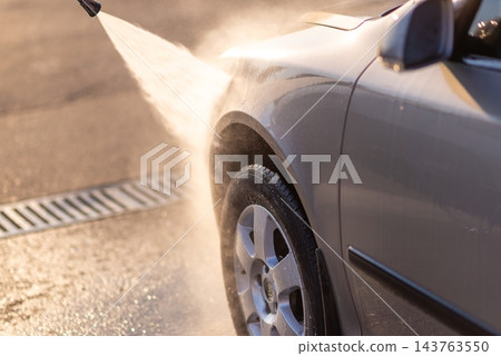 High pressure water stream spraying onto side door of gray car High pressure water stream spraying onto side door of gray car 143763550