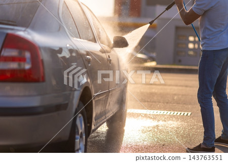Man washing his car by high pressure water gun Man washing his car by high pressure water gun 143763551