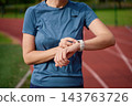 Woman checking smartwatch on running track at stadium 143763726