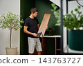 Man holding a wooden shelf and checking the metal bracket before installation 143763727