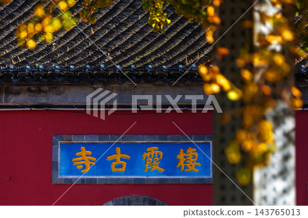 Qixia Ancient Temple in Nanjing China, red wall with blue plaque, golden ginkgo leaves in autum 143765013