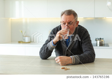Middle aged senior man holding medical pill and glass of water. Mature old senior grandfather taking medication cure pills vitamin. Age prescription medicine healthcare therapy concept 143765196