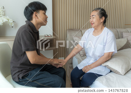 Senior woman receiving care from young man at home for wellness support Senior woman receiving care from young man at home for wellness support 143767828