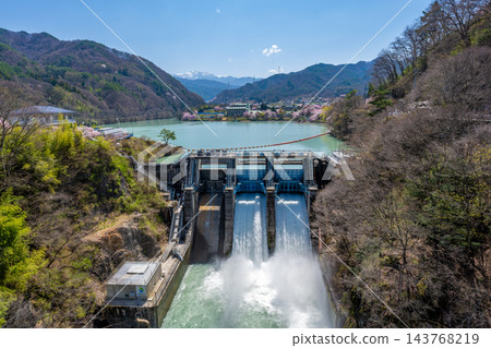 日本長野縣高戶水壩：在晴朗的藍天下，高戶水壩從高戶湖洩洪，在春意盎然的山脈映襯下，激起強烈的水花。 143768219