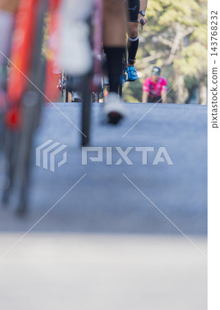 Runner takes a stride along a road during an outdoor race in daylight 143768232