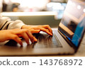 Close-up of hands working on a laptop keyboard. Young woman using laptop computer. Freelance 143768972