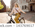 Young woman with curly hair enjoys a sunny day while posing with her bicycle. Eco transport. 143769017