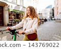 Happy woman rides electric scooter at weekend leisure time. Ecological transport. Active lifestyle. 143769022
