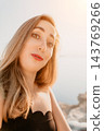Woman portrait surprise portrait of a young woman with a surprised expression posing outdoors near the sea at sunset during vacation 143769266