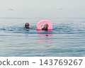 Family swimming sea mother and daughter enjoy summer vacation together with pink inflatable ring in calm blue water 143769267