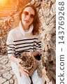 Woman cat pet smiling woman in striped sweater holding tabby cat near stone wall in warm outdoor sunlight showing affection 143769268