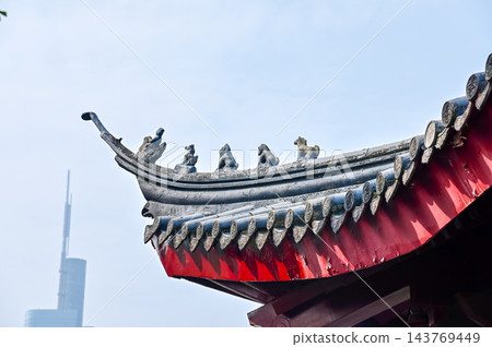 Close-up of the ornate decor on the Chinese classic roof of traditional building, Chinese architecture in China. Chinese folk religion landmark. Buddhist Temple or traditional building. Close-up of the ornate decor on the Chinese classic roof of traditional building, Chinese architecture in China. Chinese folk religion landmark. Buddhist Temple or traditional building. 143769449