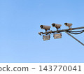 Surveillance Cameras and Security CCTV Mounted on Pole Overlooking Urban Area Against Blue Sky 143770041