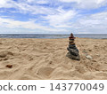 Stacked Stones Cairn on Sandy Beach by the Sea with Blue Sky, Zen Balance and Tranquility 143770049