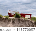 Red Boat On Sand Dune Beach With Overcast Cloudy Sky And Coastal Vegetation 143770057