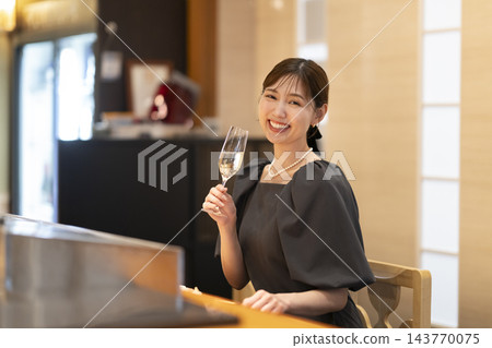 一位女士在日本餐廳的吧台享用香檳。 143770075