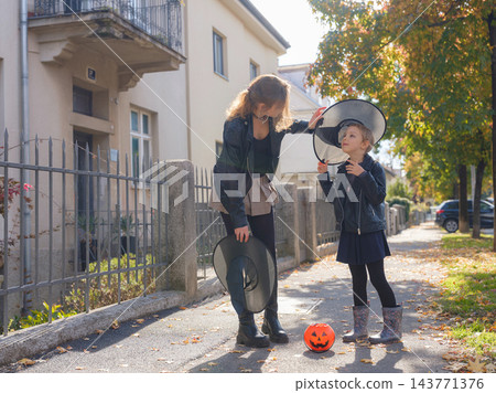 Mother and daughter enjoying Halloween trick or treat in neighborhood Mother and daughter enjoying Halloween trick or treat in neighborhood 143771376