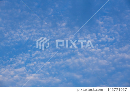 Aerial view of soft white clouds spread across a blue sky in a tranquil atmospheric pattern 143771937