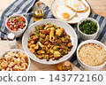 Traditional Brazilian feijao tropeiro served on a rustic ceramic plate, accompanied by eggs, pork rinds and a fresh tomato vinaigrette. 143772160