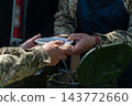 Ukrainian soldiers serving food from thermal containers outdoors 143772660