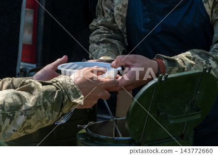 Ukrainian soldiers serving food from thermal containers outdoors 143772660