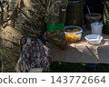 Ukrainian soldiers serving food from thermal containers outdoors 143772664