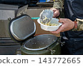 Ukrainian soldiers serving food from thermal containers outdoors 143772665