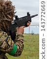 Ukrainian soldier in ghillie helmet holding an assault rifle outdoors 143772669