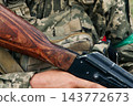 Ukrainian soldier in ghillie helmet holding an assault rifle outdoors 143772673