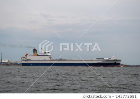 cargo ship sailing on calm ocean near industrial port area with side view from water level showing metal and composite materials cargo ship sailing on calm ocean near industrial port area with side view from water level showing metal and composite materials 143772681
