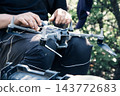 Person inspecting or preparing a quadcopter drone outdoors 143772683
